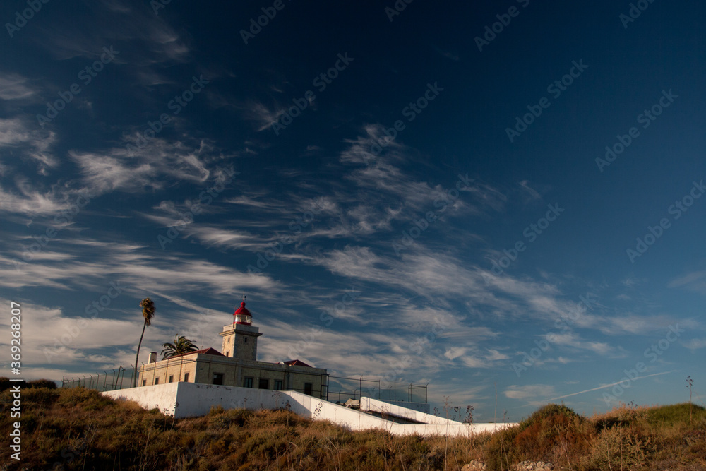 Lighthouse in the avternoon. Bright blue sky with clouds, windy weather. Portugal