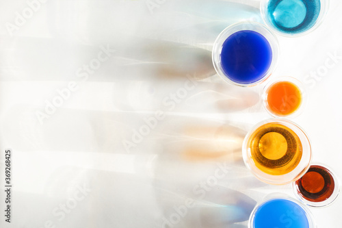 Trendy top view of glasses filled with colotful liquids and their shadows on white background. Blue and orange energetic colors, bright and juicy. Copy space photo