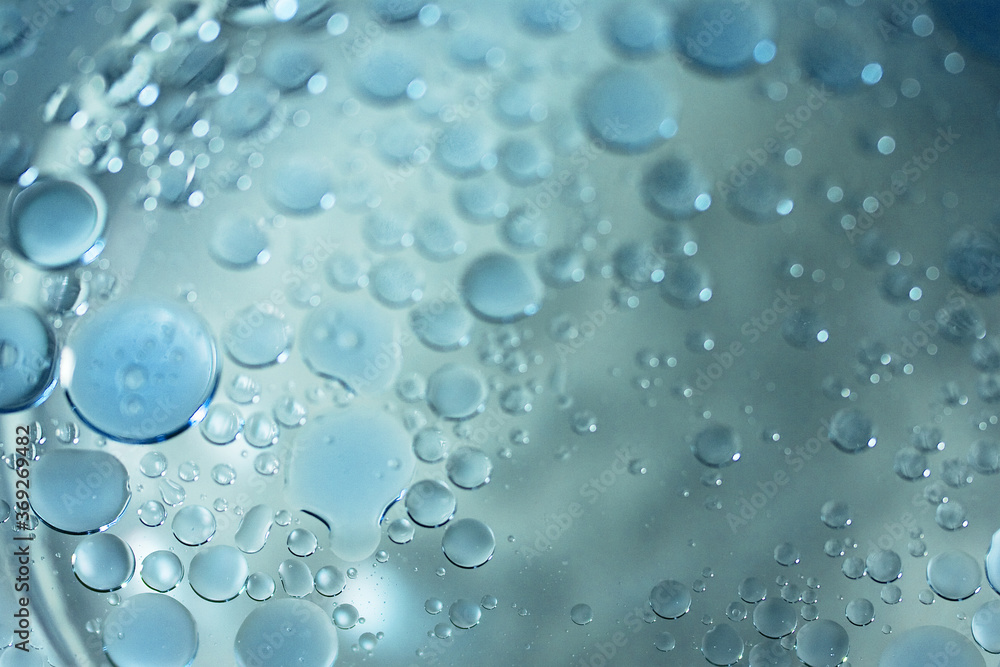 Macro view of light-blue oil bubbles in the water. Serene background with oil drops