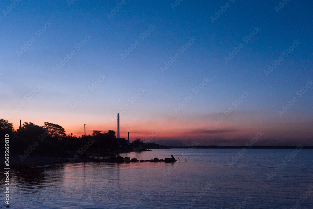 Seashore and chimney of a factory at sunrise. ​​Mariupol, Ukraine