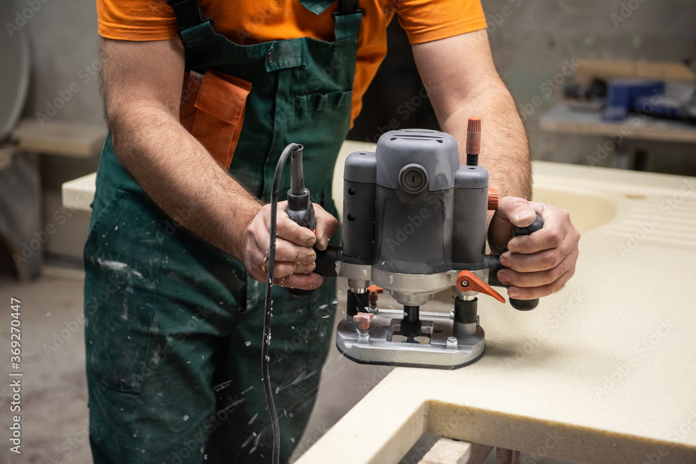 Stone sink furniture production. Carpenter polishes the surface of the sink with a grinder
