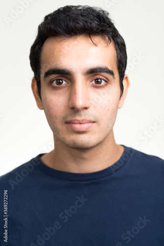 Portrait of young handsome Indian man against white background