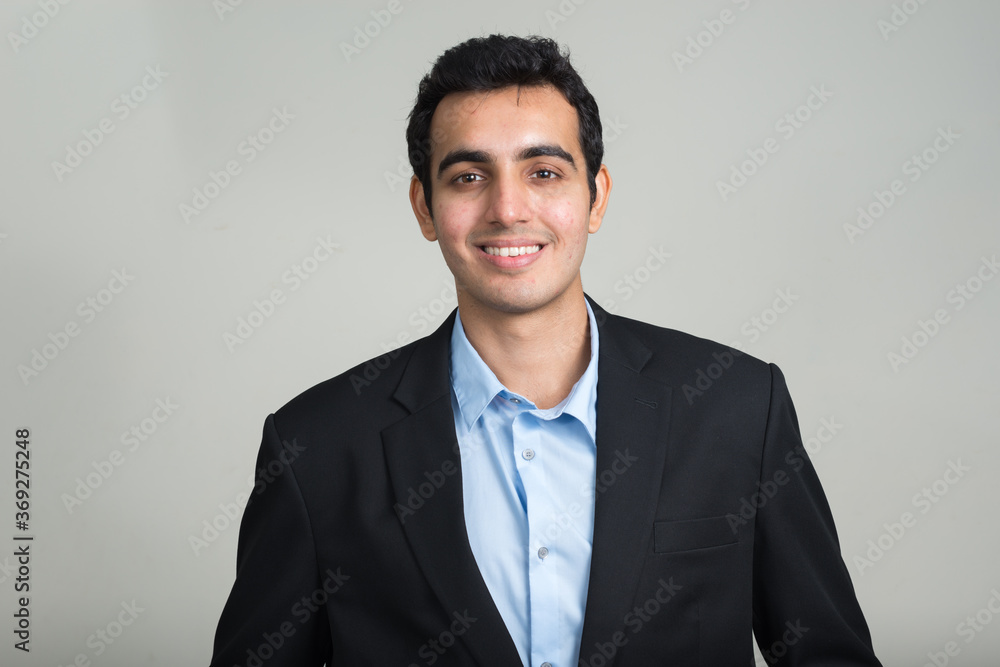 Portrait of happy young handsome Indian businessman in suit smiling Portrait of happy young handsome Indian businessman in suit smiling