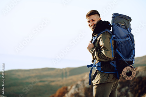 Young caucasian man traveler with big backpack hiking in the mountains