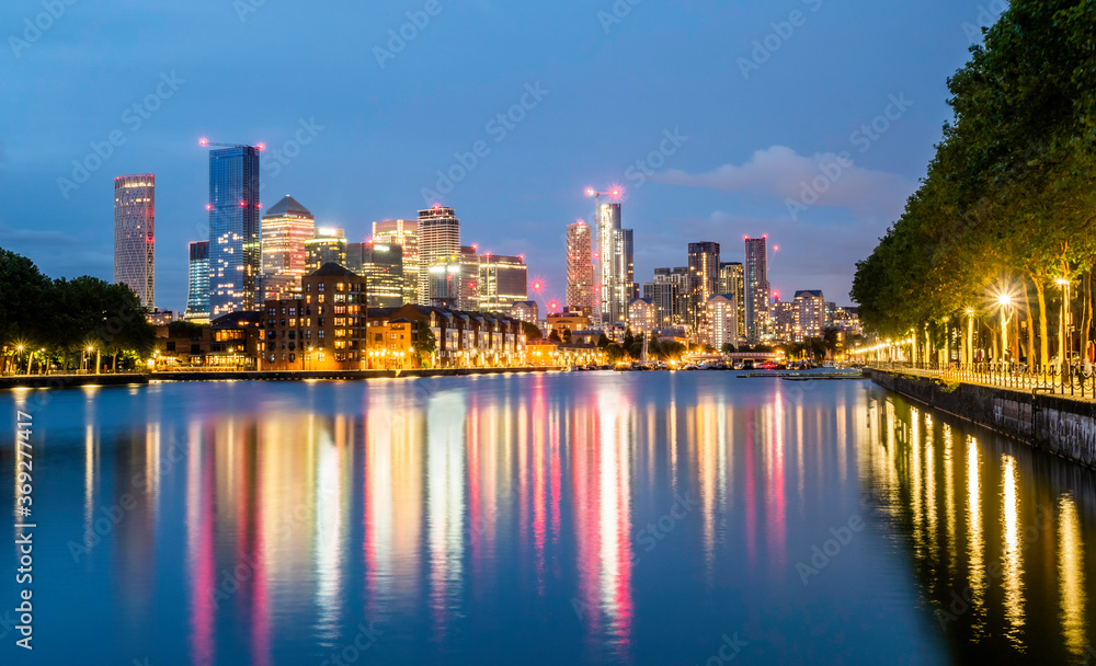 Modern buildings of the famous Financial district of London Canary Wharf reflected on the Thames river at blue hour in England