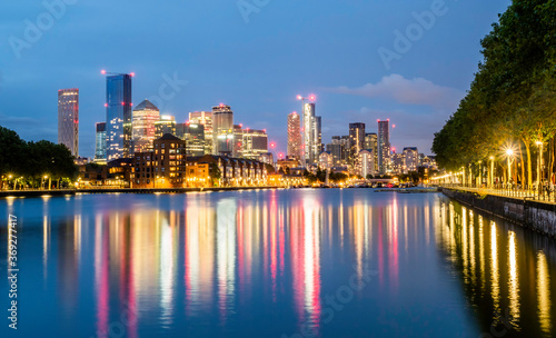 Modern buildings of the famous Financial district of London Canary Wharf reflected on the Thames river at blue hour in England © cristianbalate