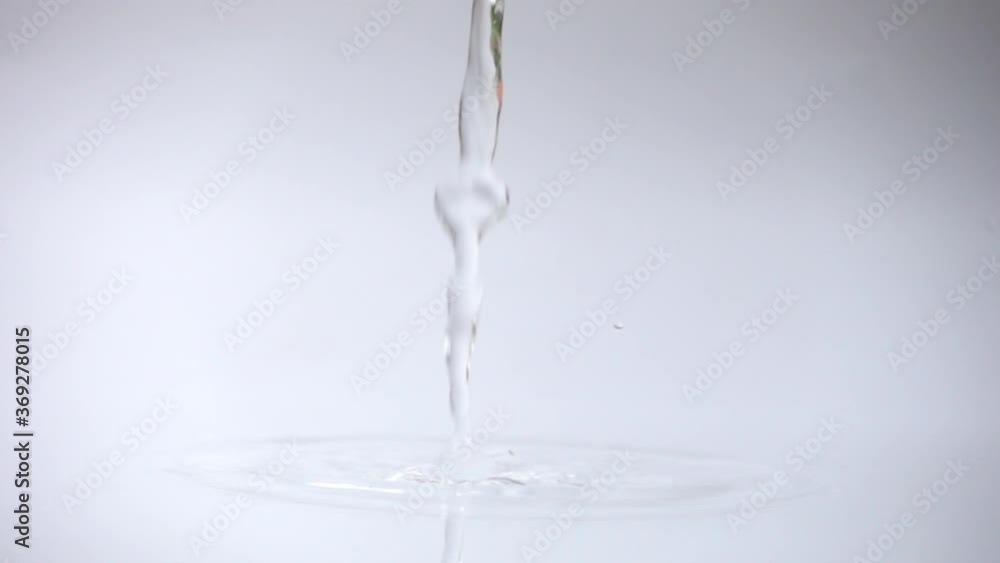 Pour water to water surface in container over white background in slow motion. Pour water to water surface in container over white background in slow motion.