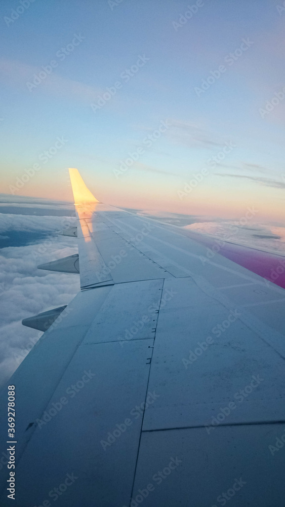 The left wing of a flying plane from the window above the clouds. The left wing of a flying plane from the window above the clouds.
