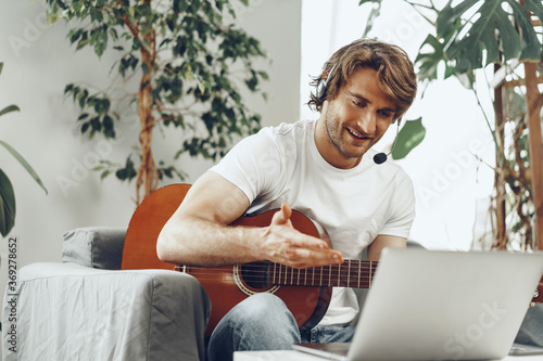 Young man watching guitar tutorial on his laptop