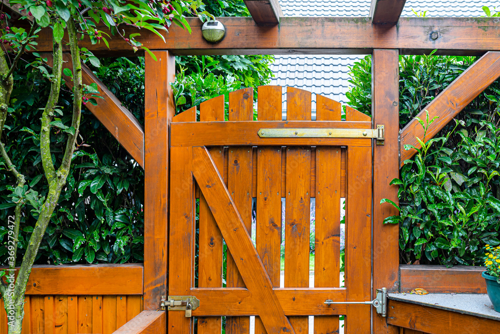 Wooden gate and fence on the back of the home garden. The gate is