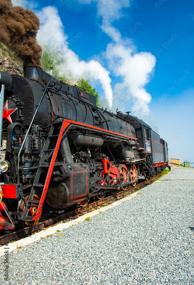 Obraz premium a retro steam train takes tourists for a journey by the Circum-Baikal Railway, a historic rail road. The Circum-Baikal is one of the picturesque sights of the area around Lake Baikal.