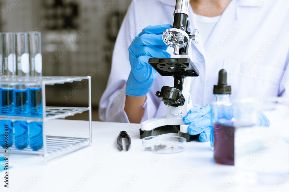 Fototapeta premium Medical Research asian Scientist Working With Microscope Doing Research Making Scientific Experiment, Works in a Bright Modern Laboratory.