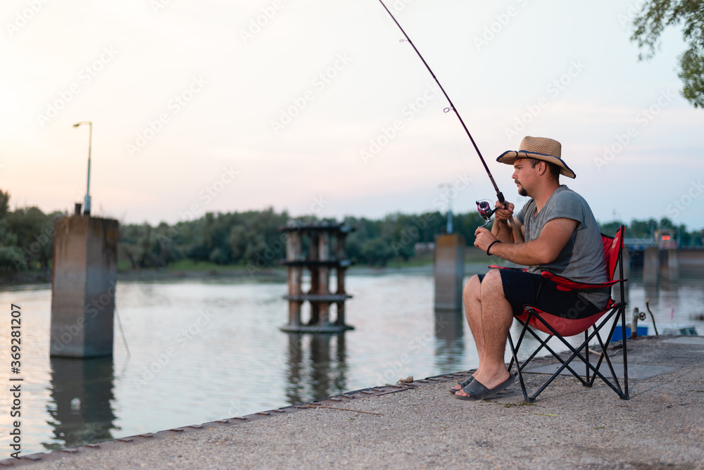 Young attractive man fishing from river bank