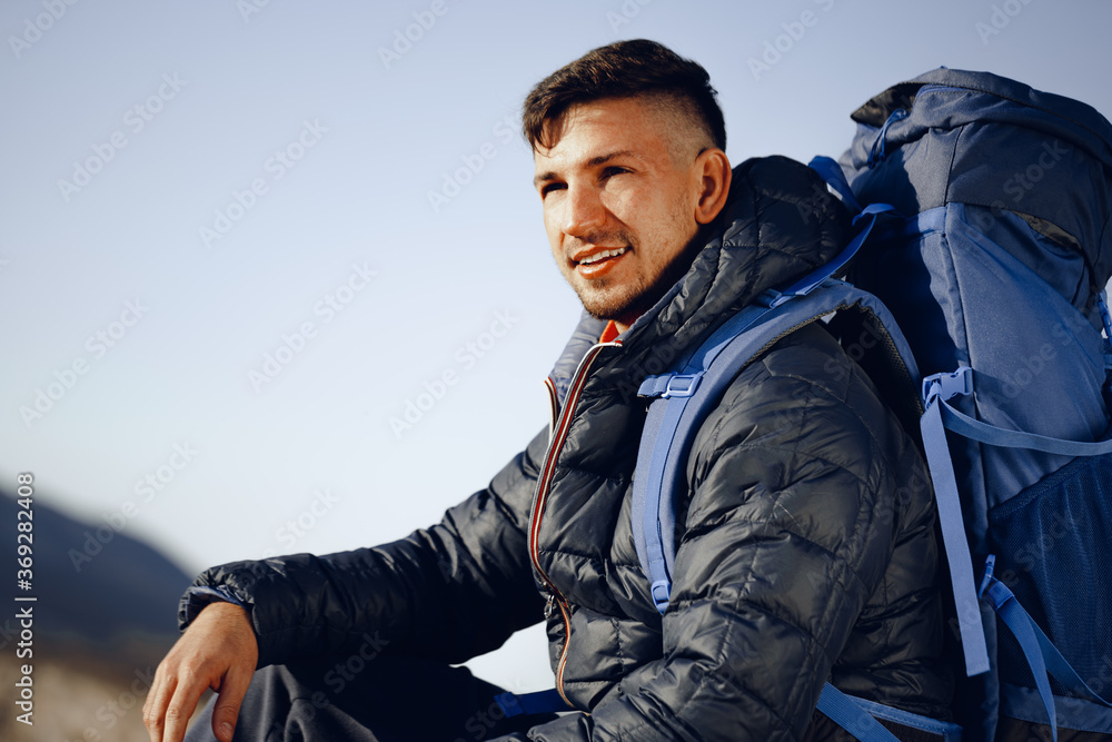 Portrait of a young caucasian man hiking in the mountains - obrazy, fototapety, plakaty 