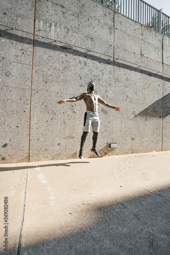 Athletic black man is training in urban area while wearing a mask. © haizon
