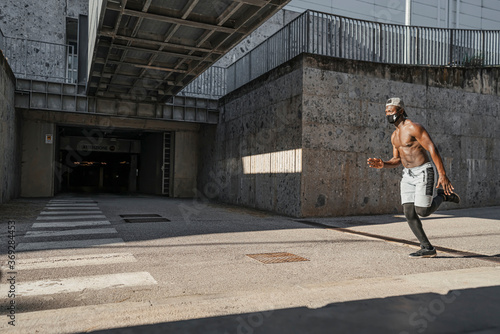 Athletic black man is training in urban area while wearing a mask. © haizon