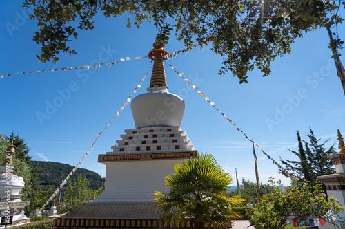 Estupa de templo budista con banderines y árbol  photo