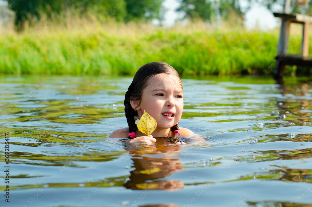 Fototapeta premium Close up of young beautiful girl in water. Portrait child swimming in the river. Six years caucasian child on vacation. Holiday and summer concept.