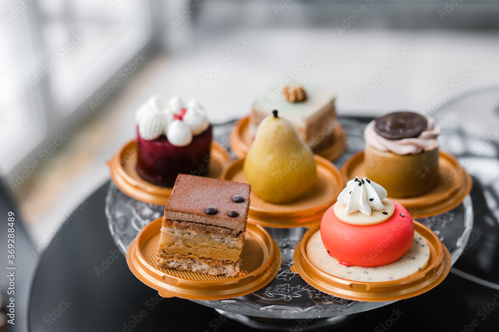 several cakes of different colors on a glass stand