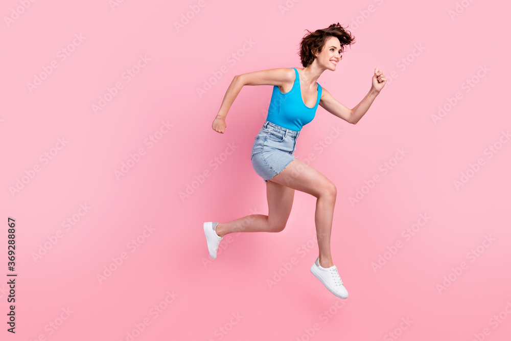 Full body size profile photo of charming pretty sporty young girl hold fists night running park smiling wear denim mini skirt blue singlet sneakers isolated pink color background