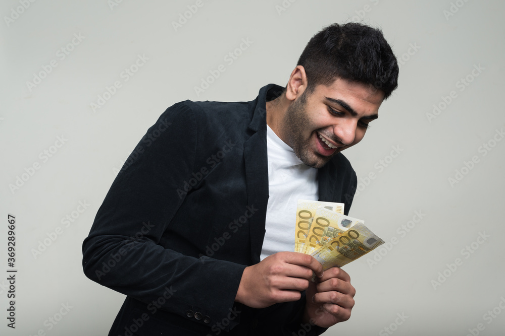 Happy young handsome bearded Indian businessman with money Happy young handsome bearded Indian businessman with money