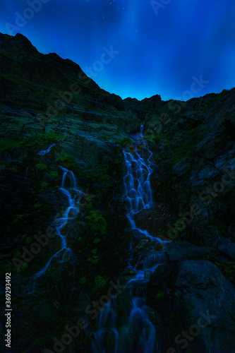 picture of a beautiful waterfall in the mountains at night with stars.