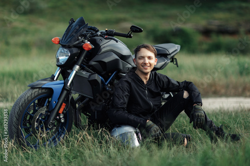Wallpaper Mural Image of biker sitting on the grass in front of motorcycle in sunset on the country road. Torontodigital.ca