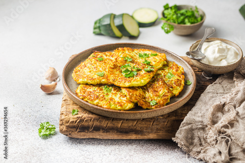 Bild auf Leinwand Green zucchini fritters, vegetarian zucchini pancakes with fresh herbs and garli