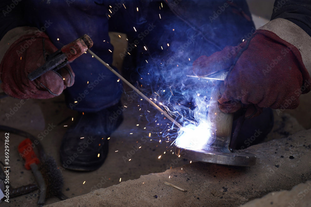 Close-up welder working with electrode at semi-automatic arc welding in manufacture production plant.Bright sparks from welding. Close-up welder working with electrode at semi-automatic arc welding in manufacture production plant.Bright sparks from welding.