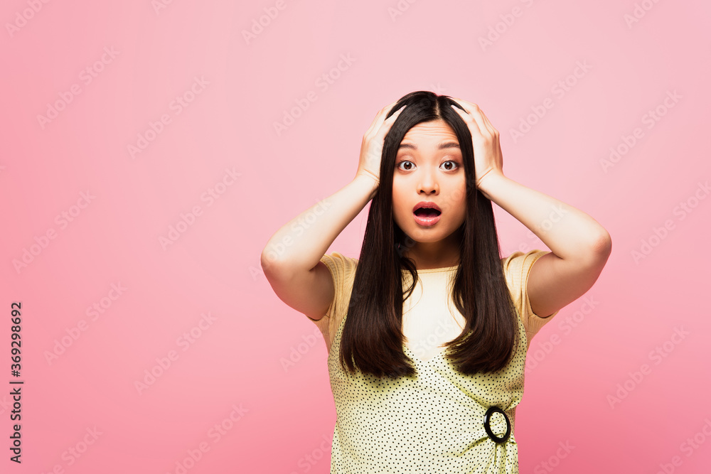 shocked asian girl touching head and looking at camera isolated on pink shocked asian girl touching head and looking at camera isolated on pink