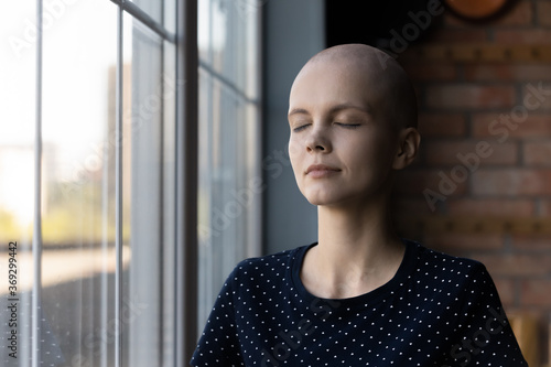 Calm young Caucasian sick hairless woman suffer from cancer meditate relieve negative emotions, relaxed ill bald female patient with oncology feel mindful peaceful, stress free, faith concept