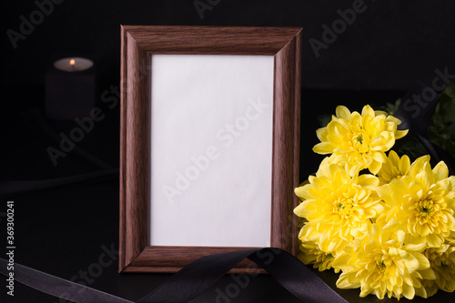 Funeral wooden frame next to yellow asters on black background