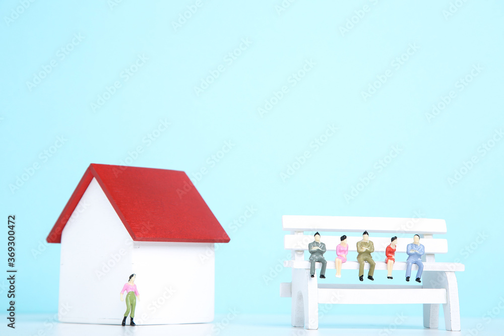 Wooden house model with miniature people on blue background