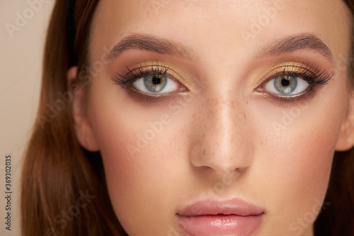 close-up of a pretty girl's face with beautiful big blue eyes, big lashes and eyebrows