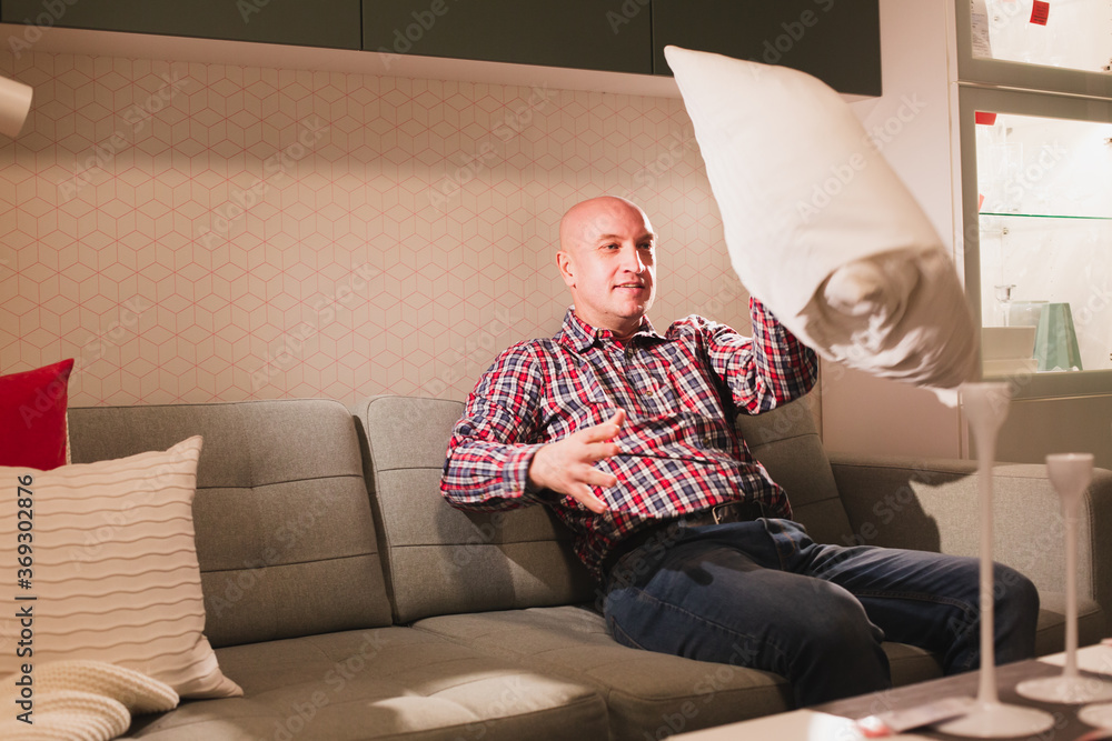 A man is sitting on a sofa with decorative pillows.
