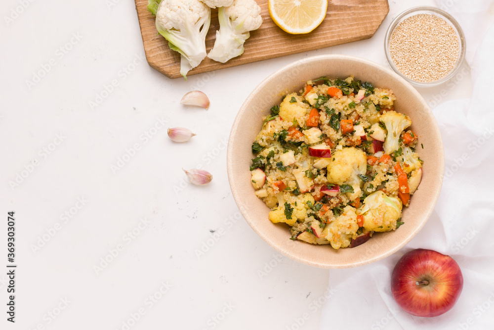 Summer salad with cauliflower, quinoa, apple in lemon sauce with parsley on a white plate. Copy space Summer salad with cauliflower, quinoa, apple in lemon sauce with parsley on a white plate. Copy space