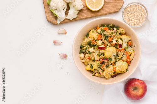 Summer salad with cauliflower, quinoa, apple in lemon sauce with parsley on a white plate. Copy space