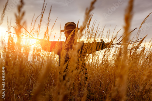 Foto Terrible scarecrow in dark cloak and dirty hat stands alone in a autumn field at sunset time