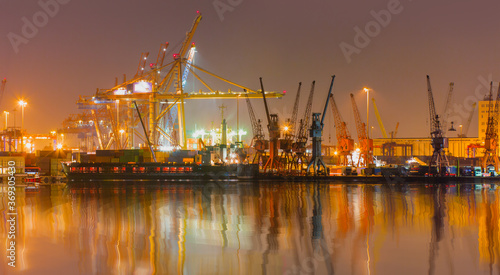 Container terminal in industrial port with cranes - Ship loading in port with busy port at night - Mersin, Turkey