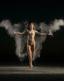 Dancer posing in flying powder on black background
