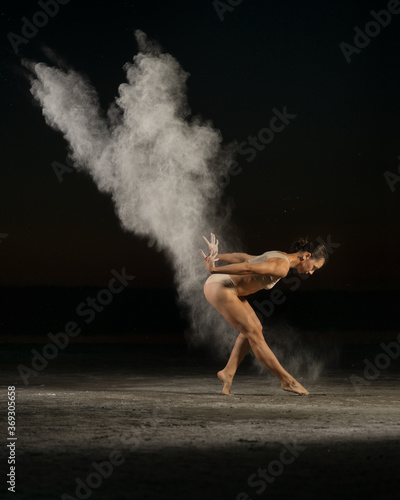 Slim female acrobat in underwear throwing dust in air