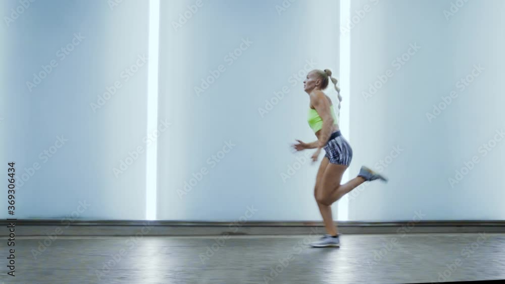 wide shot traveling to the left profile shot blonde slow motion caucasian girl with ponytail running to the left wearing fitness clothing lights and blue neon lights wide shot traveling to the left profile shot blonde slow motion caucasian girl with ponytail running to the left wearing fitness clothing lights and blue neon lights