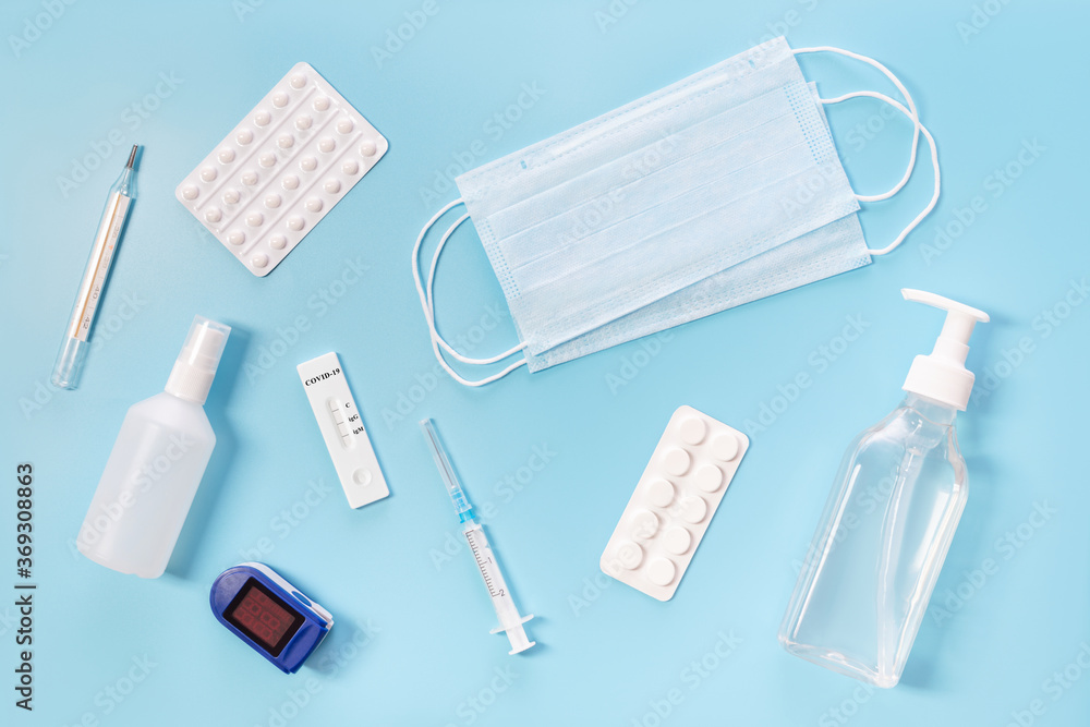Medical kit. Means for the prevention and treatment of influenza or coronavirus. Mask, sanitizer, test, pulse oximeter and medication on a blue background. Medical kit. Means for the prevention and treatment of influenza or coronavirus. Mask, sanitizer, test, pulse oximeter and medication on a blue background.