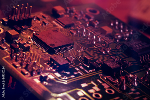 Close-up. Red neon abstract tech computer background. Printed circuit board (PCB) and electronic components of the chip. Artificial intelligence and technology photo