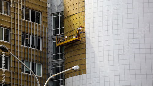 worker builder making construction for ventilation facade on a building with screwdriver drill photo