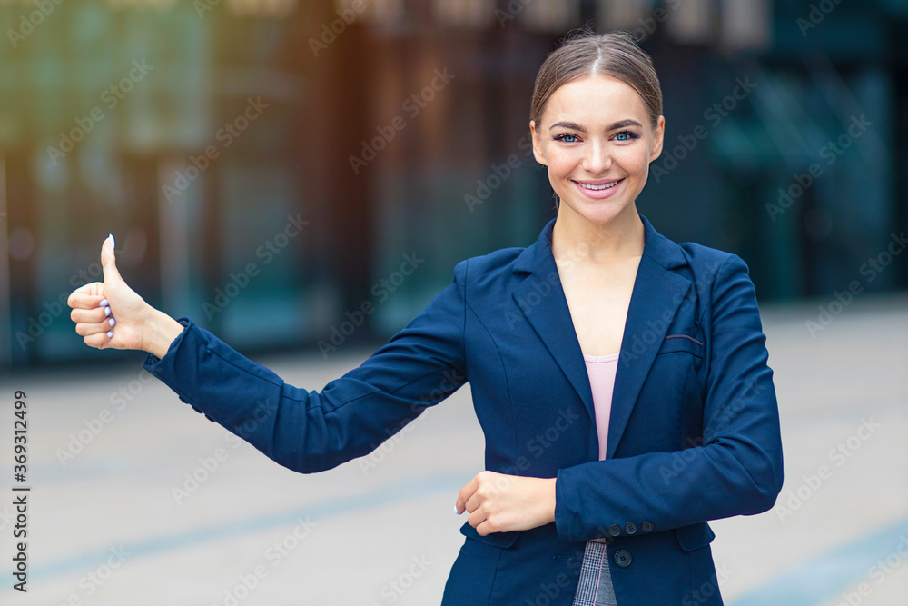 Portrait of beautiful young businesswoman or positive student in suit, formal blue jacket showing thumb up, like gesture outdoors. Happy cheerful geourgeous woman, pretty girl look at camera, smiling Portrait of beautiful young businesswoman or positive student in suit, formal blue jacket showing thumb up, like gesture outdoors. Happy cheerful geourgeous woman, pretty girl look at camera, smiling