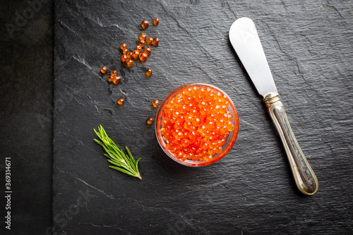 Delicious red caviar on black slate background, top view