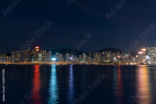 Hong Kong cityscape at night over Victoria Harbor with clear sky and urban skyscrapers. © KissShot
