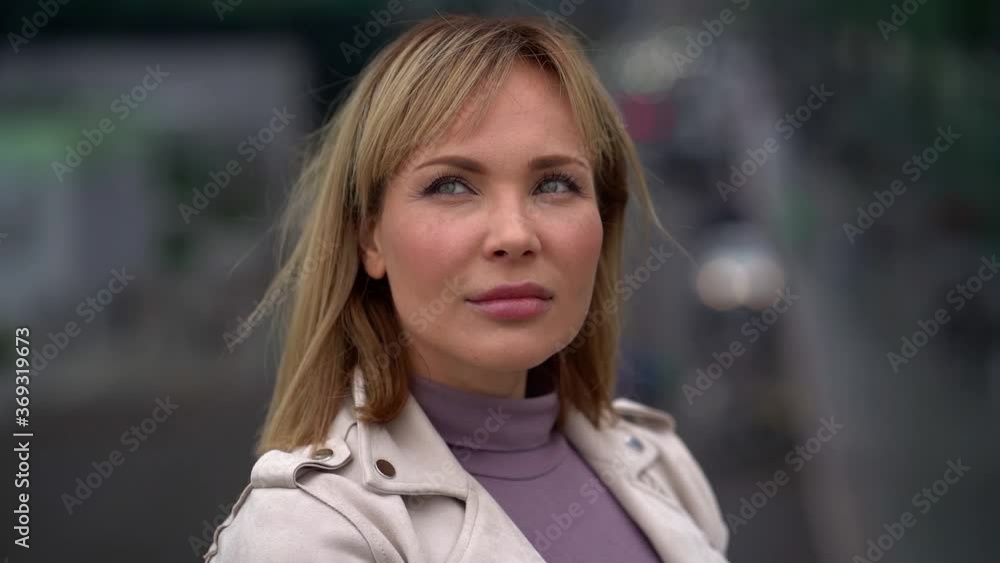 Close-up portrait of a pretty blonde who is outdoors in the city. The wind blows her hair and she poses Close-up portrait of a pretty blonde who is outdoors in the city. The wind blows her hair and she poses