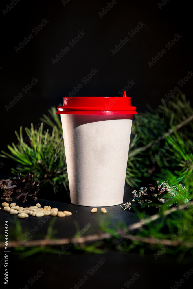 Paper cup of coffee on black background with pine tree and cedar seeds Paper cup of coffee on black background with pine tree and cedar seeds